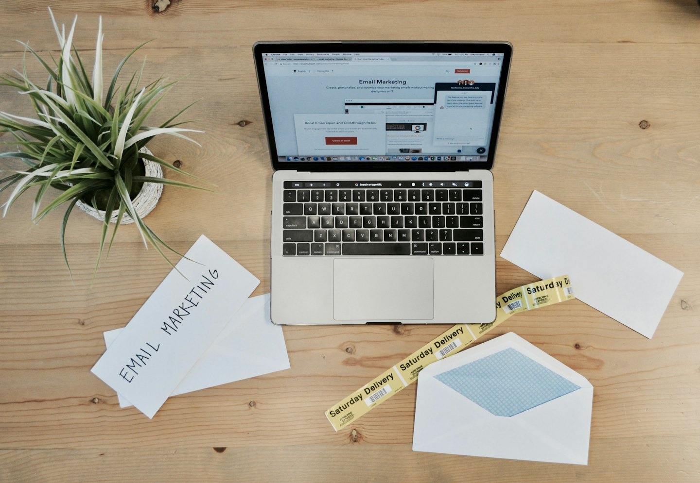 Laptop open to email marketing website on a wooden desk.
